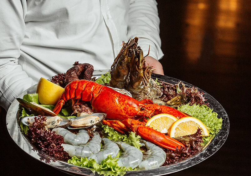 waiter-holding-seafood-platter-with-lobster-king-prawns-mussels